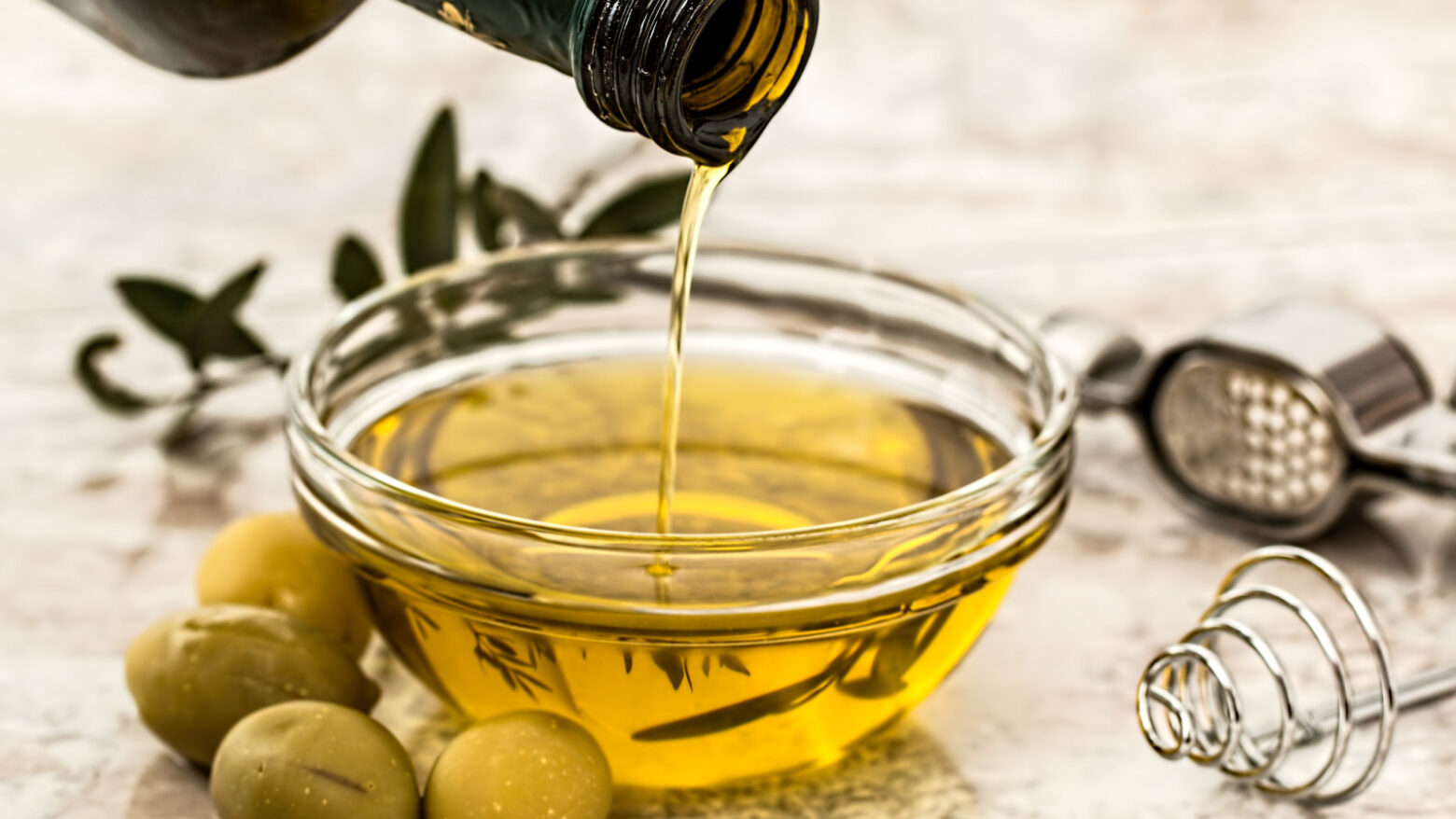 Olive oil being poured into a small glass bowl