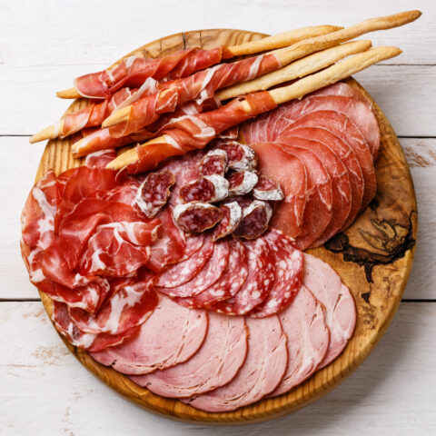 Above shot of different cuts of deli meats and salamis on a circular wooden board