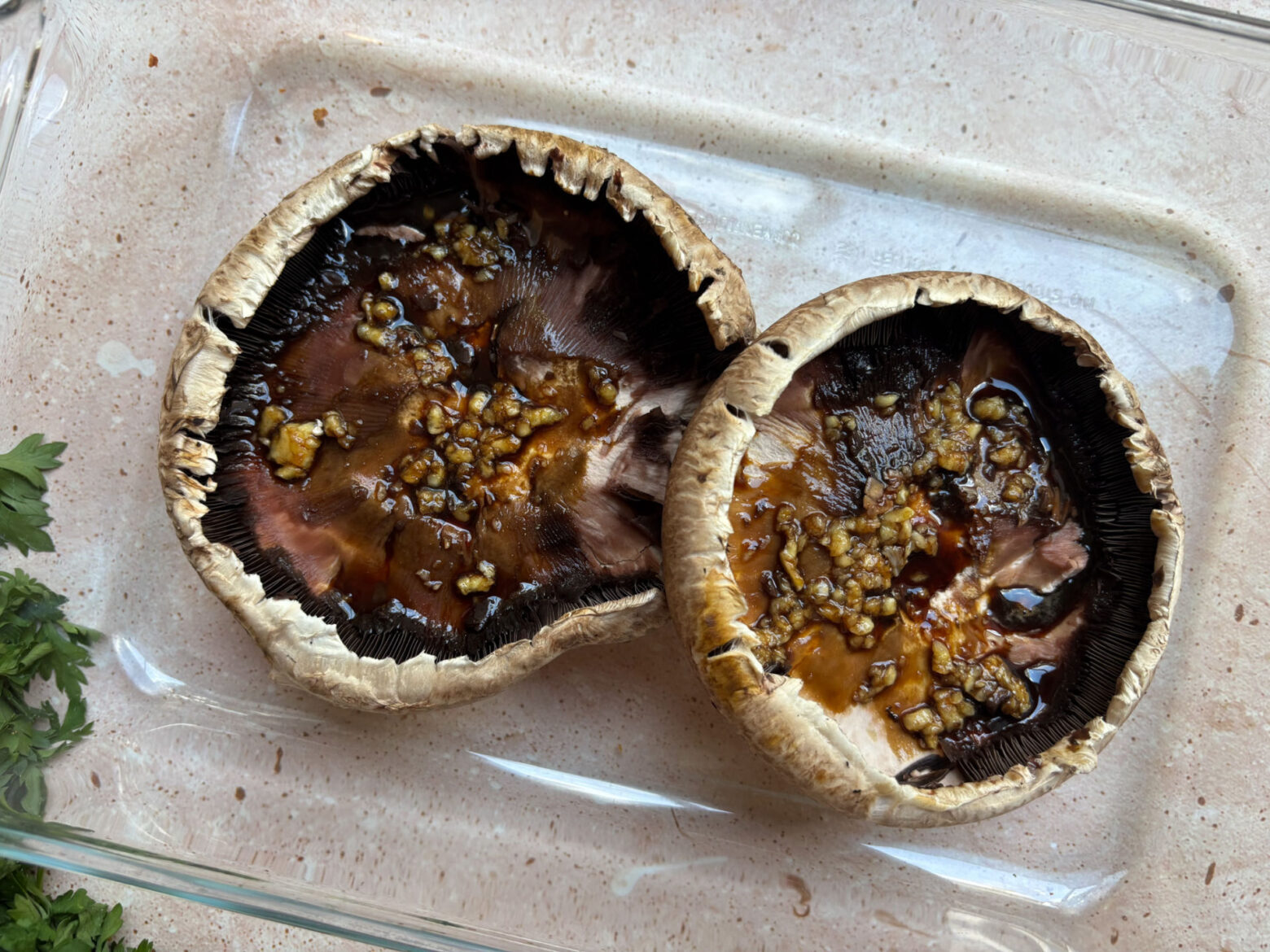 Grilled portobello mushrooms preparation in a glass container.