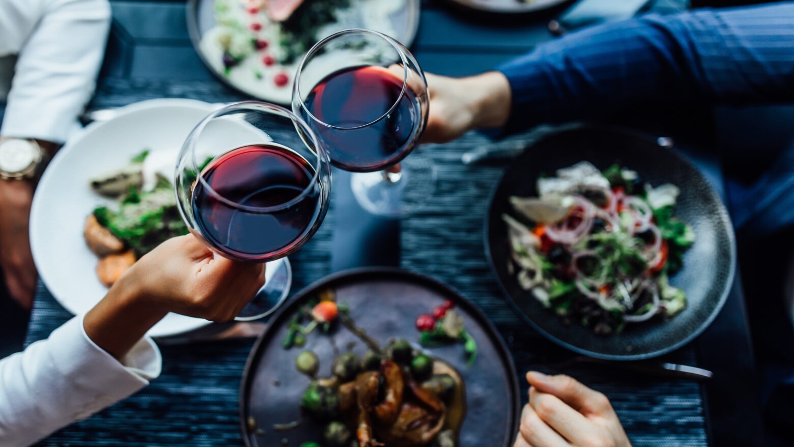 Couple giving a cheers with red wine over a healthy dinner