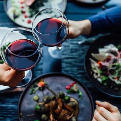 Couple giving a cheers with red wine over a healthy dinner