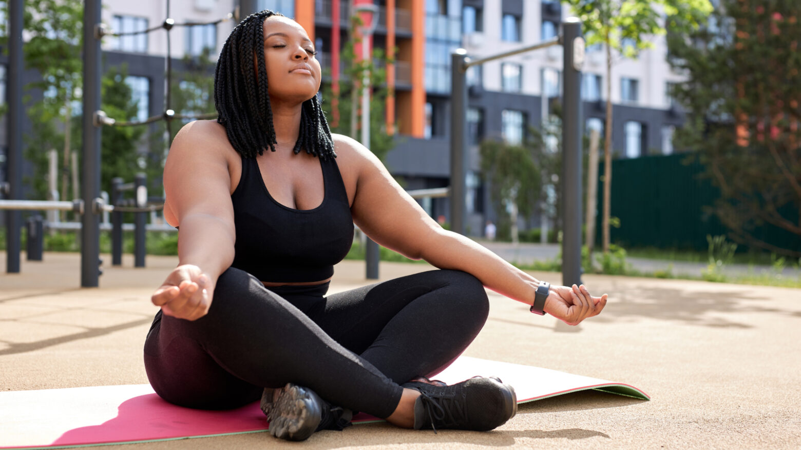 A woman meditates at the edge of a playground.