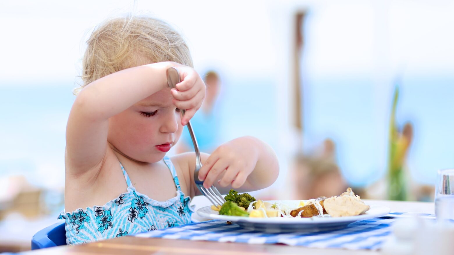 A child in a swimsuit eats lunch while on vacation