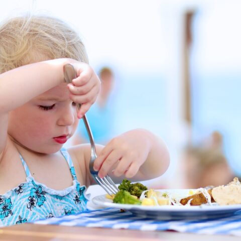 A child in a swimsuit eats lunch while on vacation