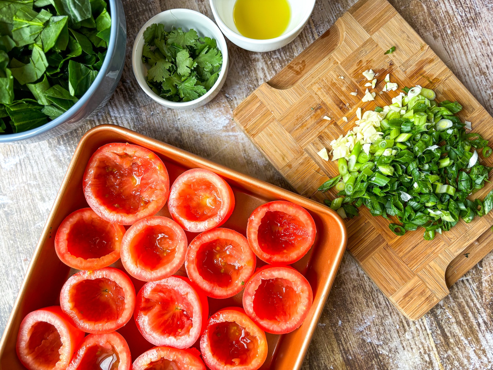 Preparing stuffed tomatoes on a tray with spinach and herbs.