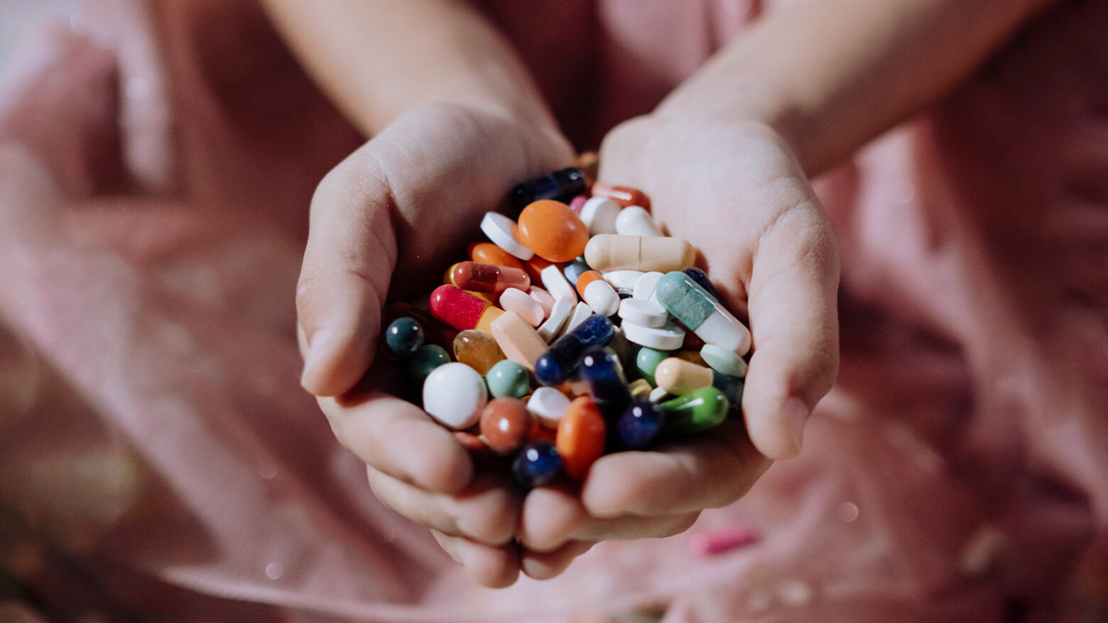 Close up of hands full of a variety of colorful pills