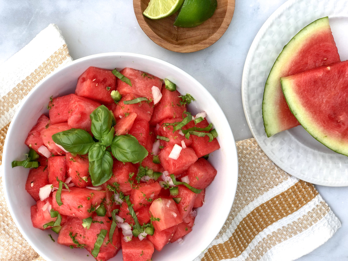 Spicy watermelon salad in a bowl with ingredients on the side.