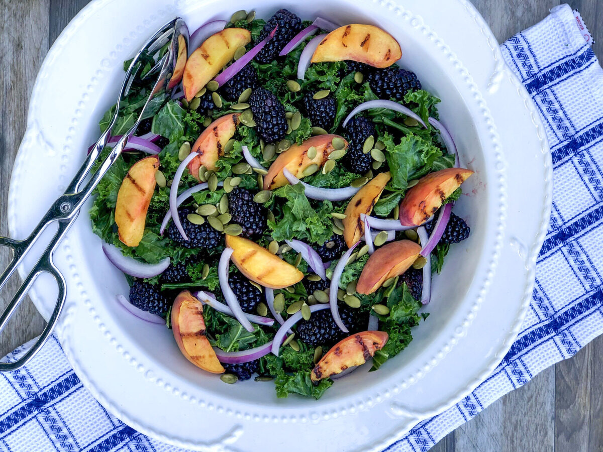 kale salad with grilled peaches in a bowl