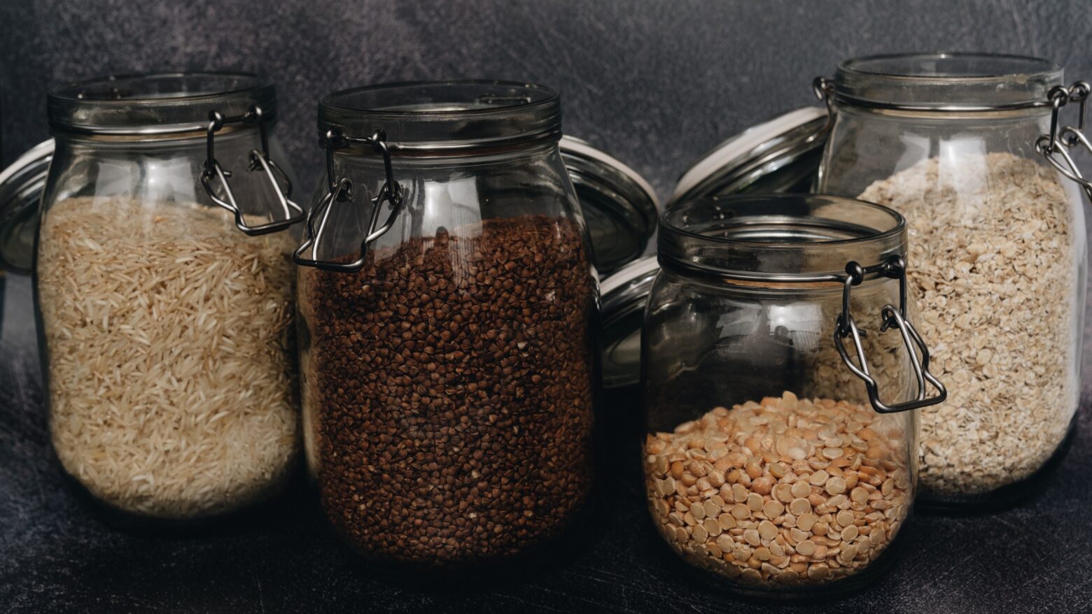 Jars of whole grains against a black background