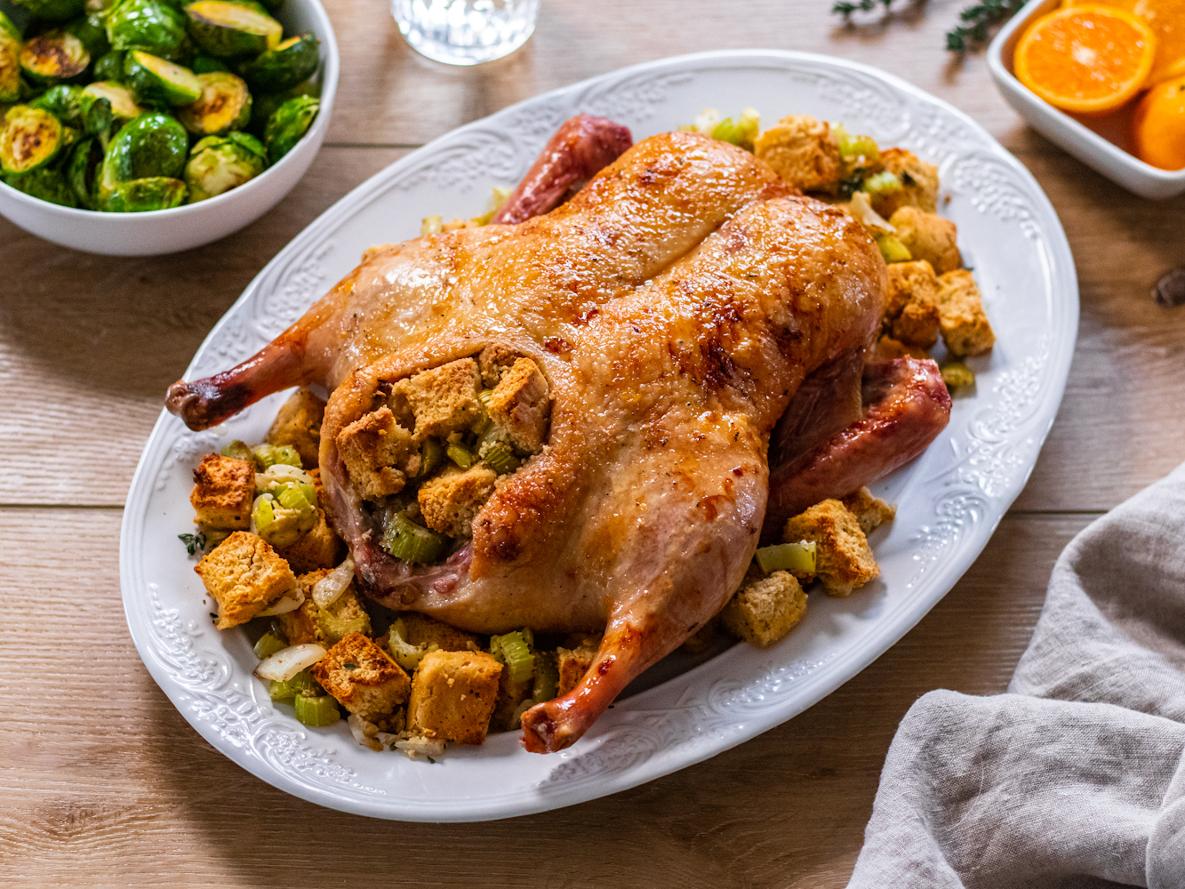 Orange Glazed Duck with Herb Stuffing, unsliced cooked duck on a plate.