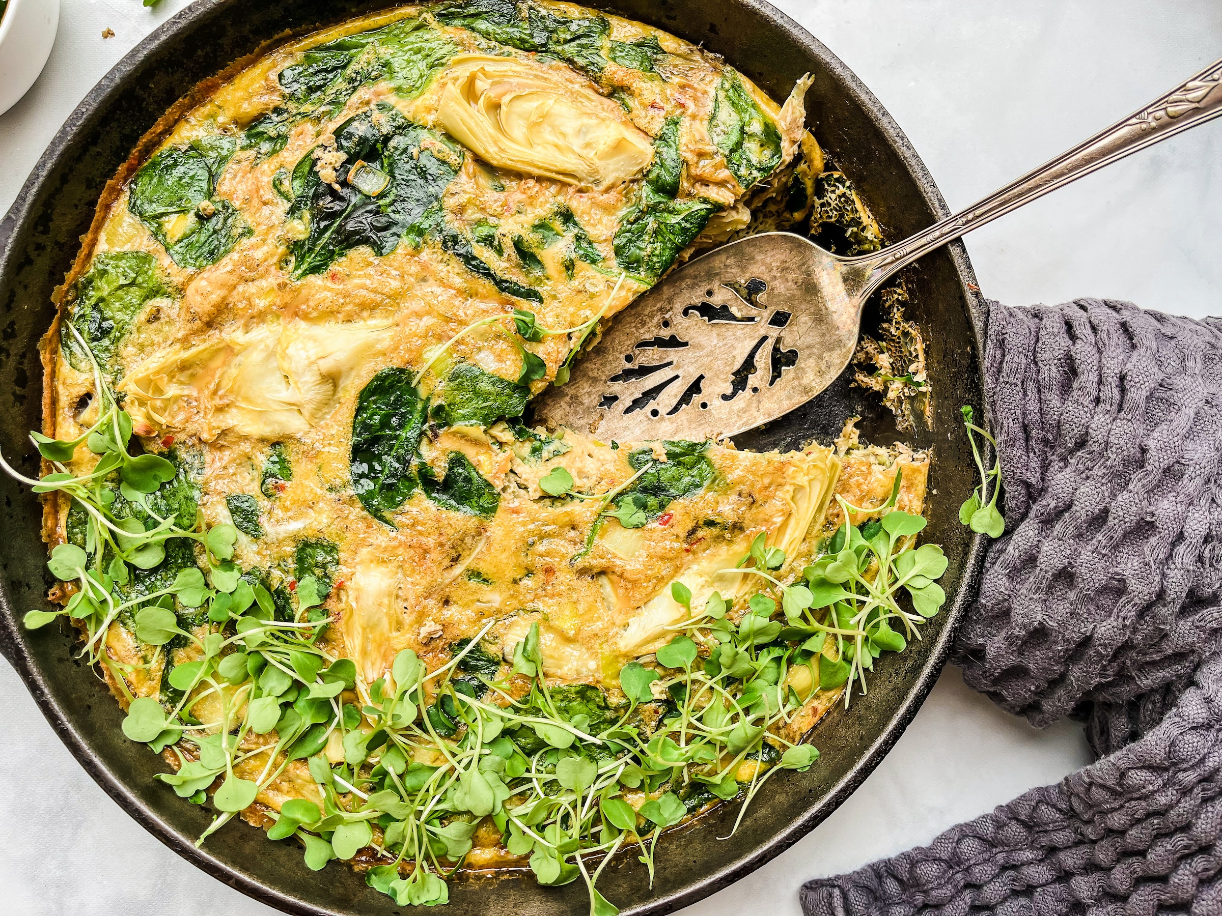 Artichoke and Spinach Frittata with a slice cut out of it. 