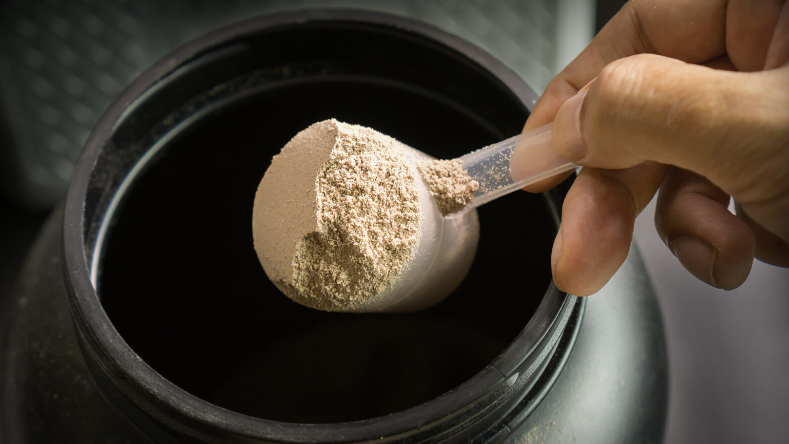 Close up of a scoop of protein powder in a hand