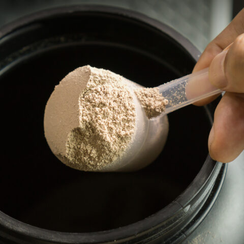 Close up of a scoop of protein powder in a hand