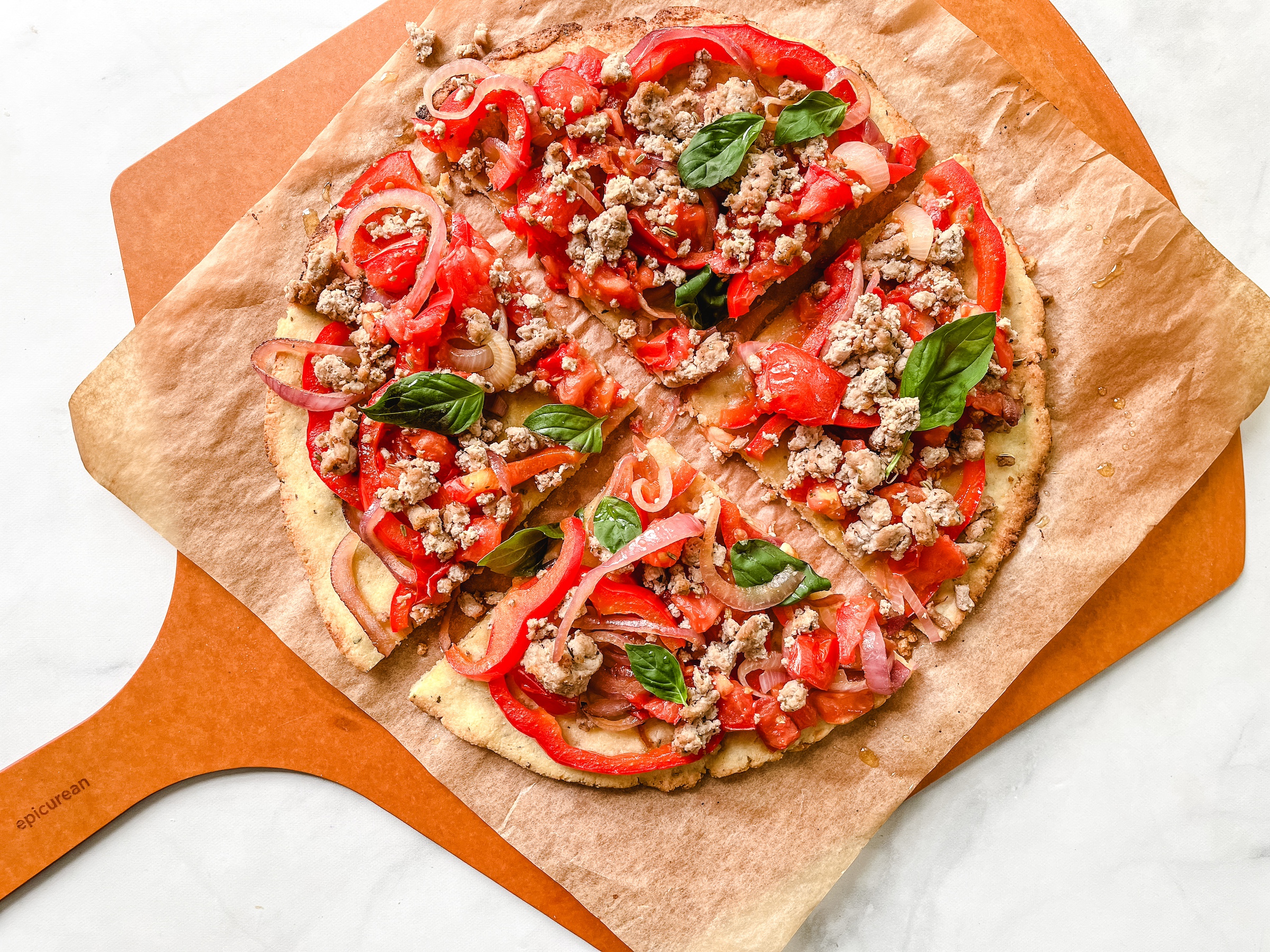 Paleo pizza on a pizza stone cut into fours.