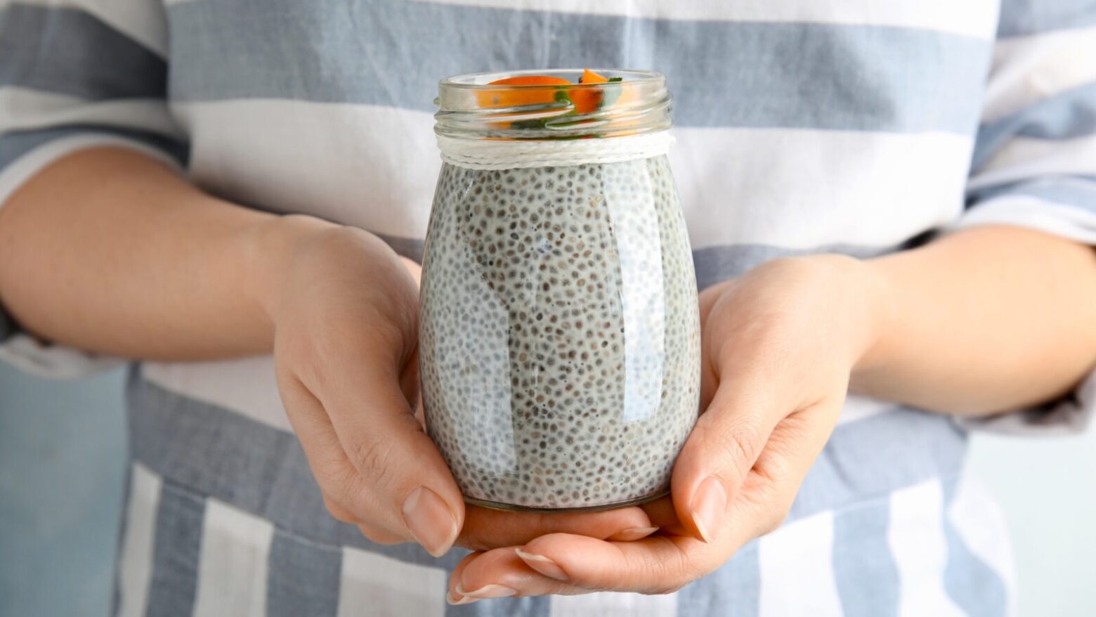 Close up of a woman holding a jar of chia pudding.