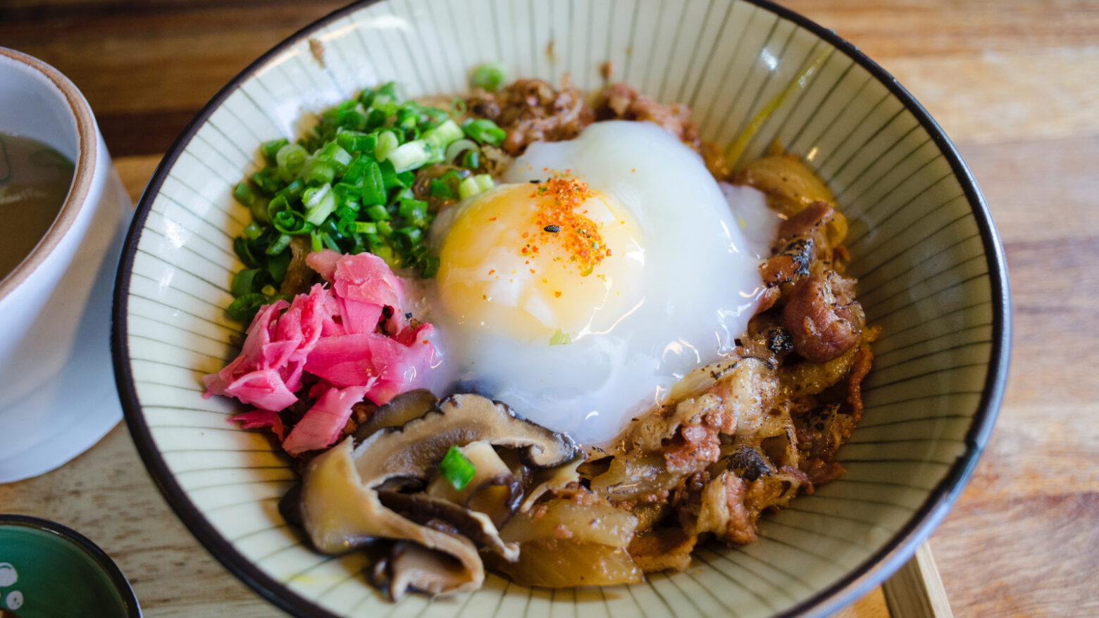 Protein bowl with egg, pickled ginger, mushrooms, bacon, and green onions