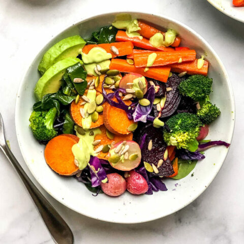 From above, a bowl of colorful mixed vegetables next to a silver fork.