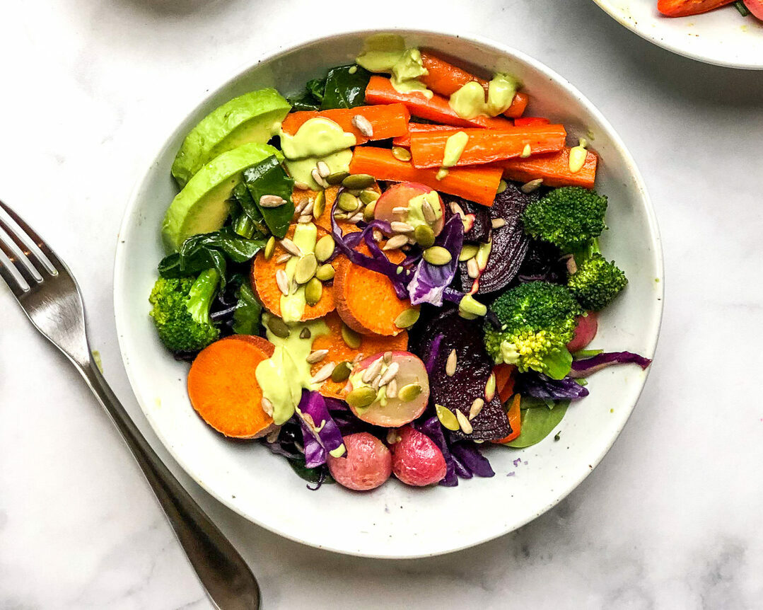From above, a bowl of colorful mixed vegetables next to a silver fork.