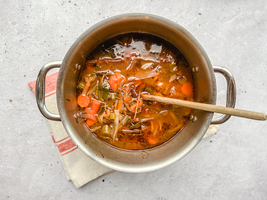 vegetable broth simmering in pot with a spoon