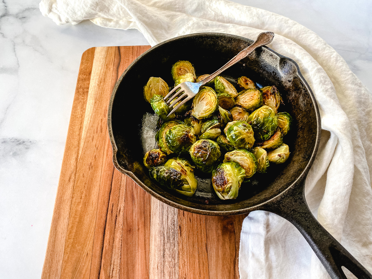 Roasted Brussels Sprouts recipe in a cast iron skillet on a wooden cutting board