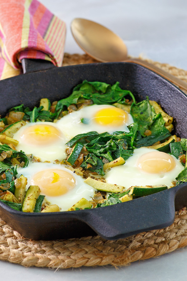 Finished green shakshuka in a cast-iron pan