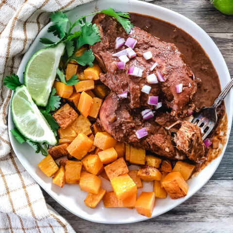 Slow cooker chicken mole on a plate with roasted butternut squash