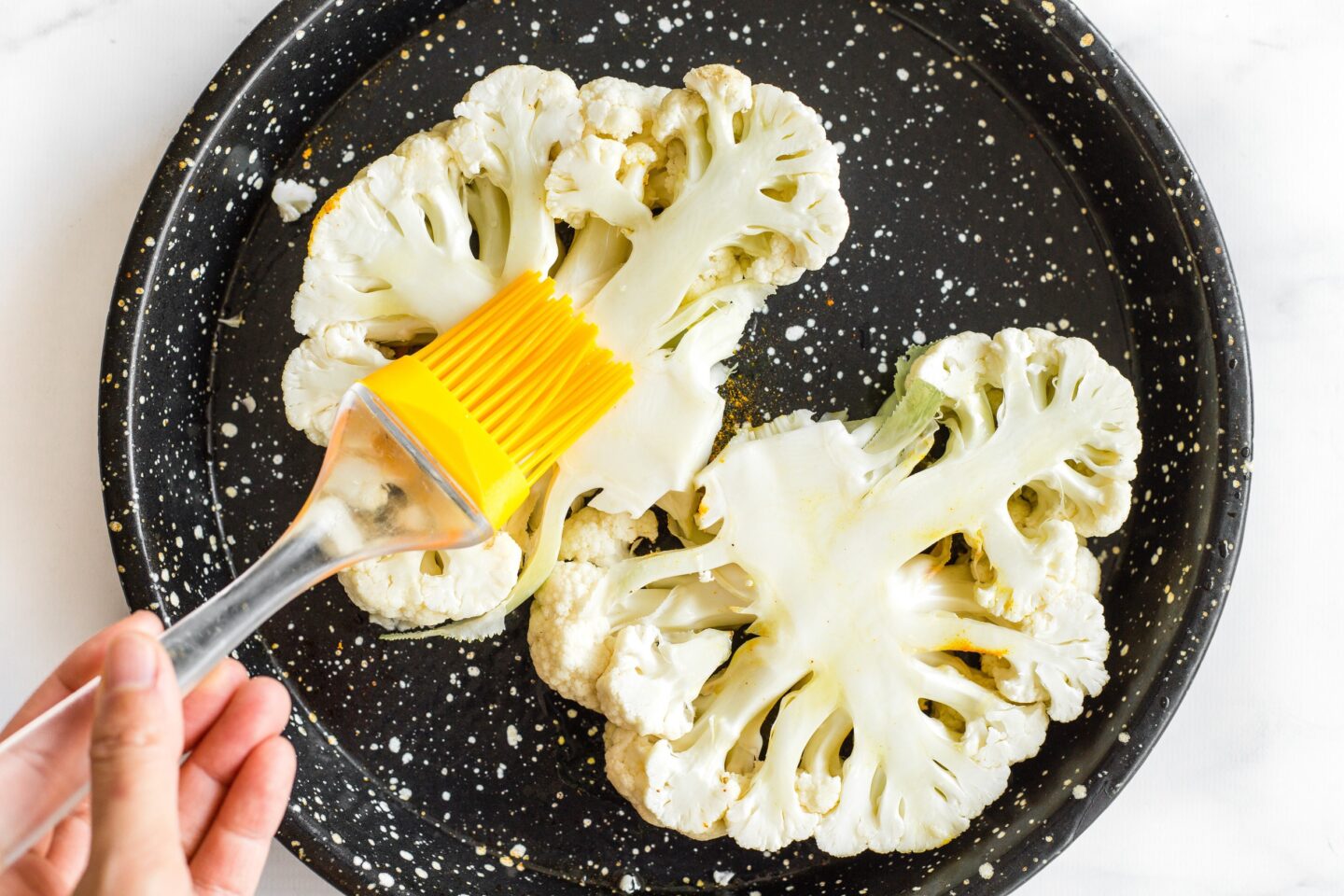 Basting sliced cauliflower steaks on a plate