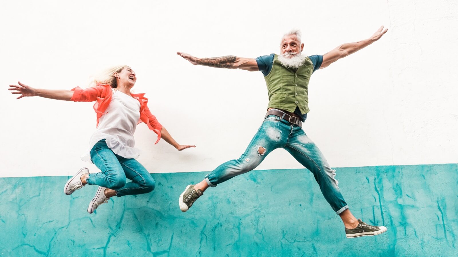 A woman and older man jumping in the air.
