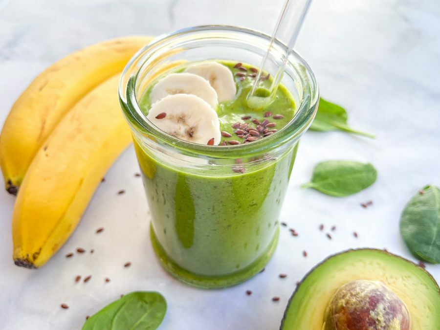 Finished avocado smoothie next to a pair of bananas