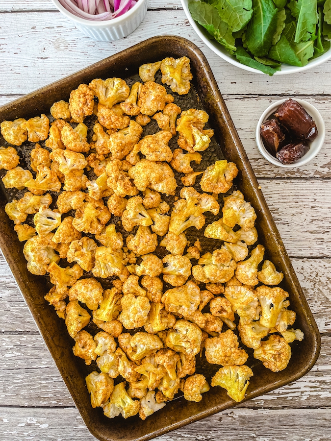 roasted cauliflower and arugula salad on baking sheet