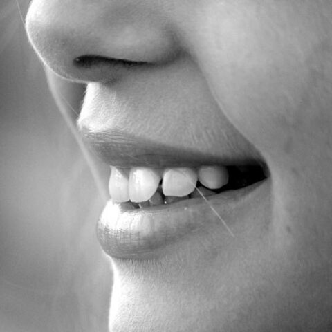 Black and white image of a person smiling and showing their teeth