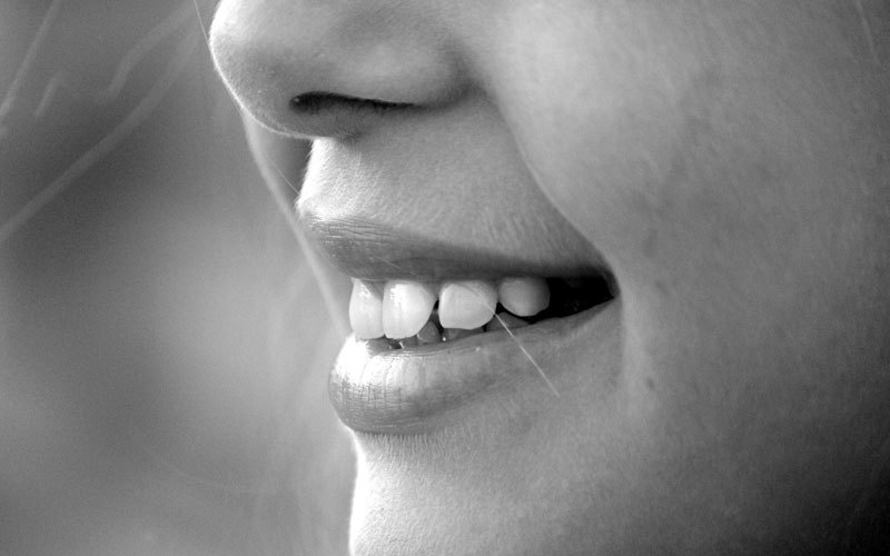 Black and white image of a person smiling and showing their teeth