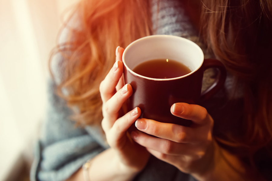 An ill person holds a mug of tea to ease her upset stomach