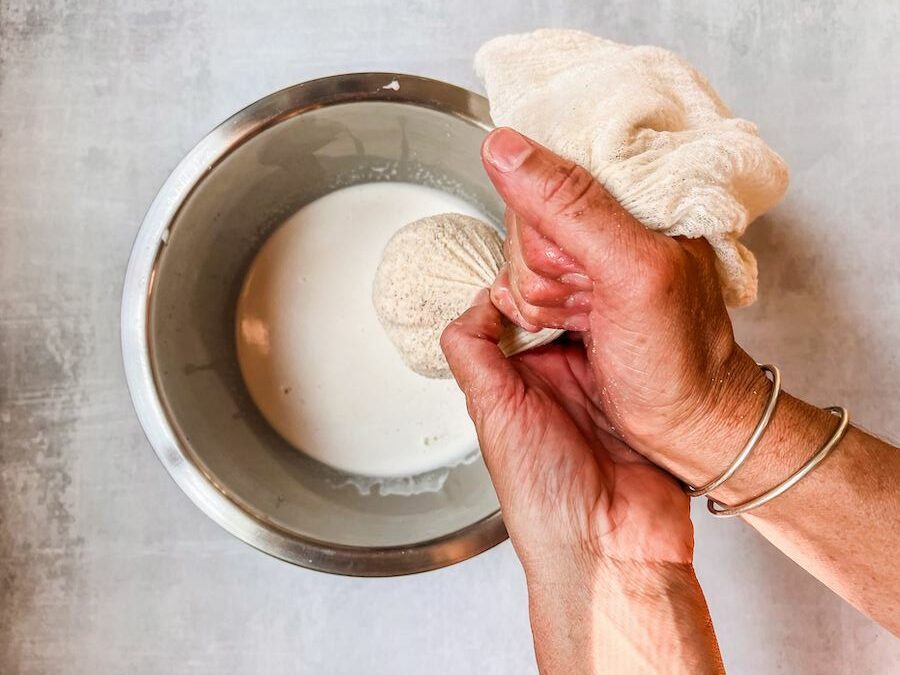 Straining almond milk through a cheesecloth