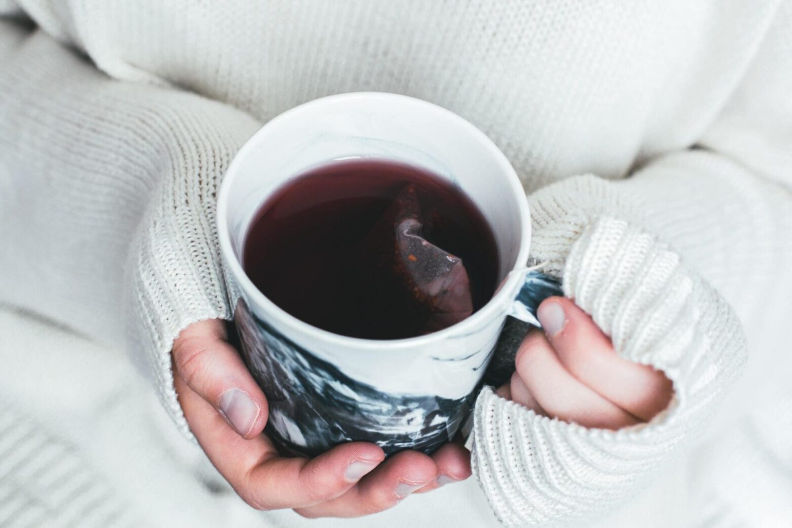 From above, hands holding a mug of herbal tea.