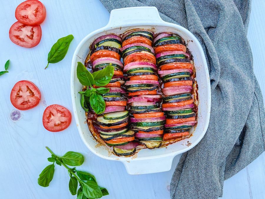 A beautiful, easy ratatouille recipe in a white crock on a table setting.