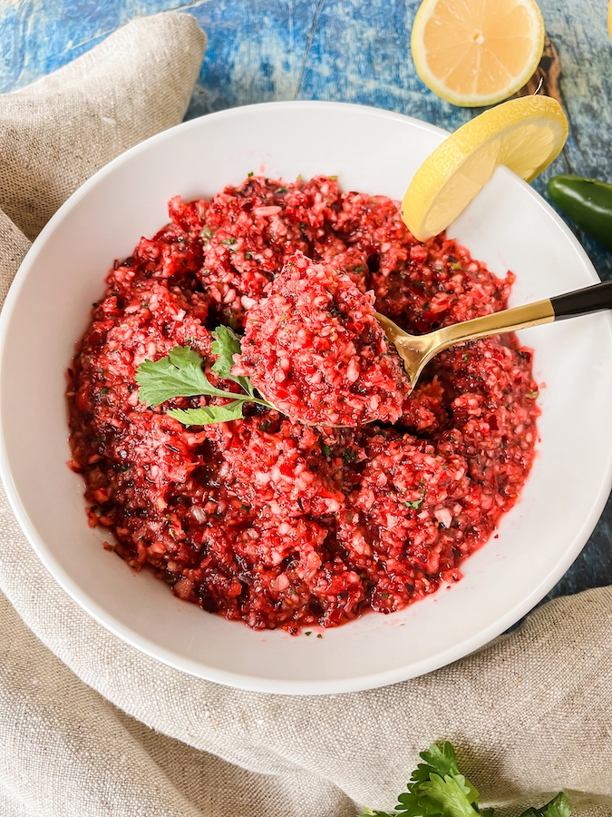 Cranberry salsa being spooned out of the bowl