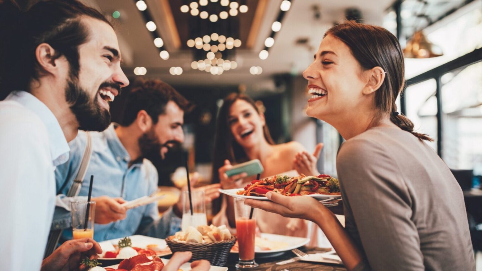 A happy group of people eating healthy food at a restaurant.