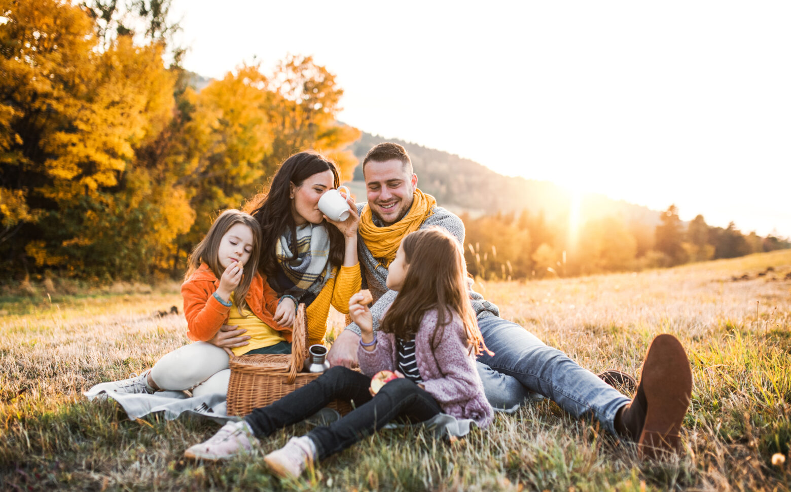 A family enjoying a fall picnic in the mountains at sunset.