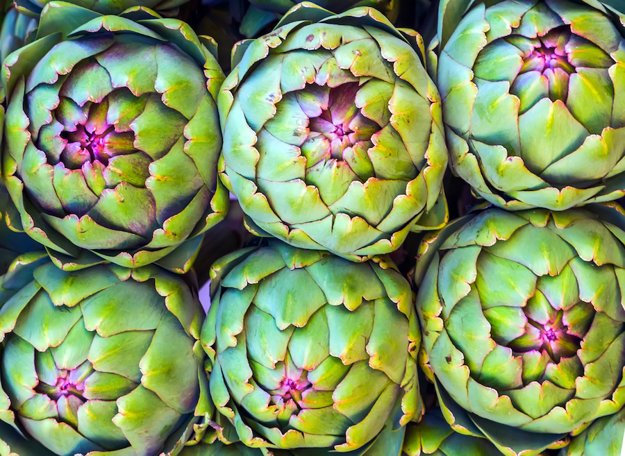 Six artichokes side-by-side from above.