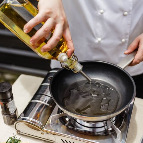 A chef pours the healthiest cooking oil onto a pan over a burner
