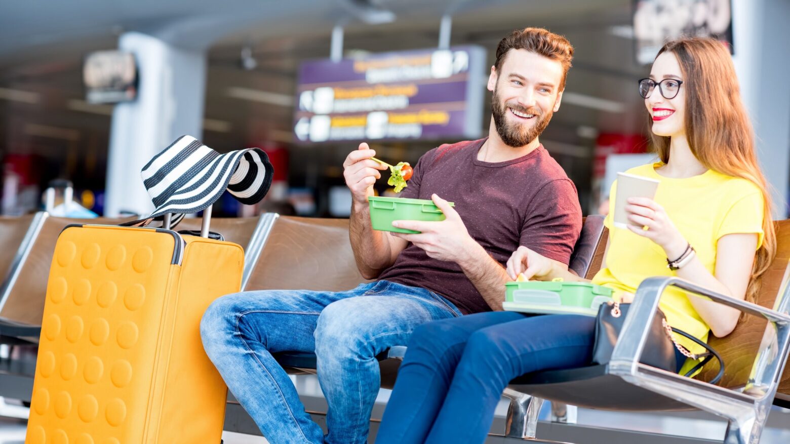 A couple sits at an airport with their Paleo travel meals