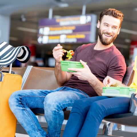 A couple sits at an airport with their Paleo travel meals