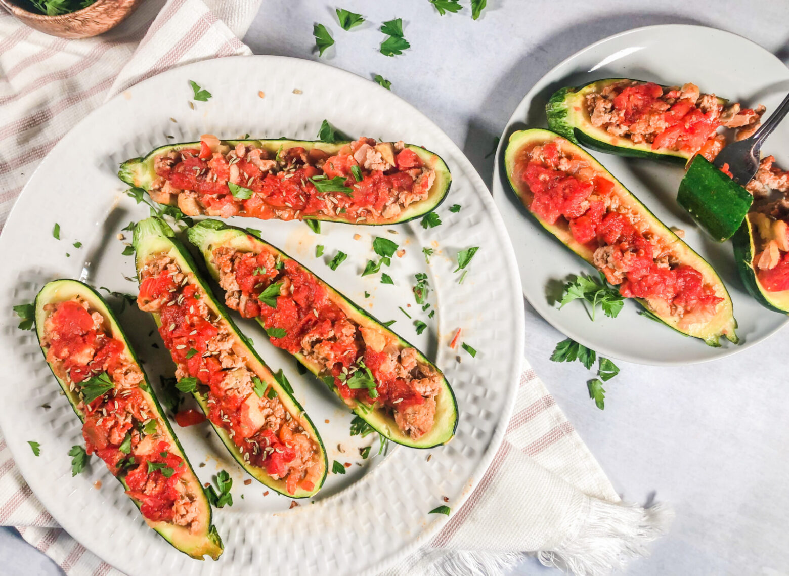 Above shot of turkey-stuffed zucchini boats on white plates.