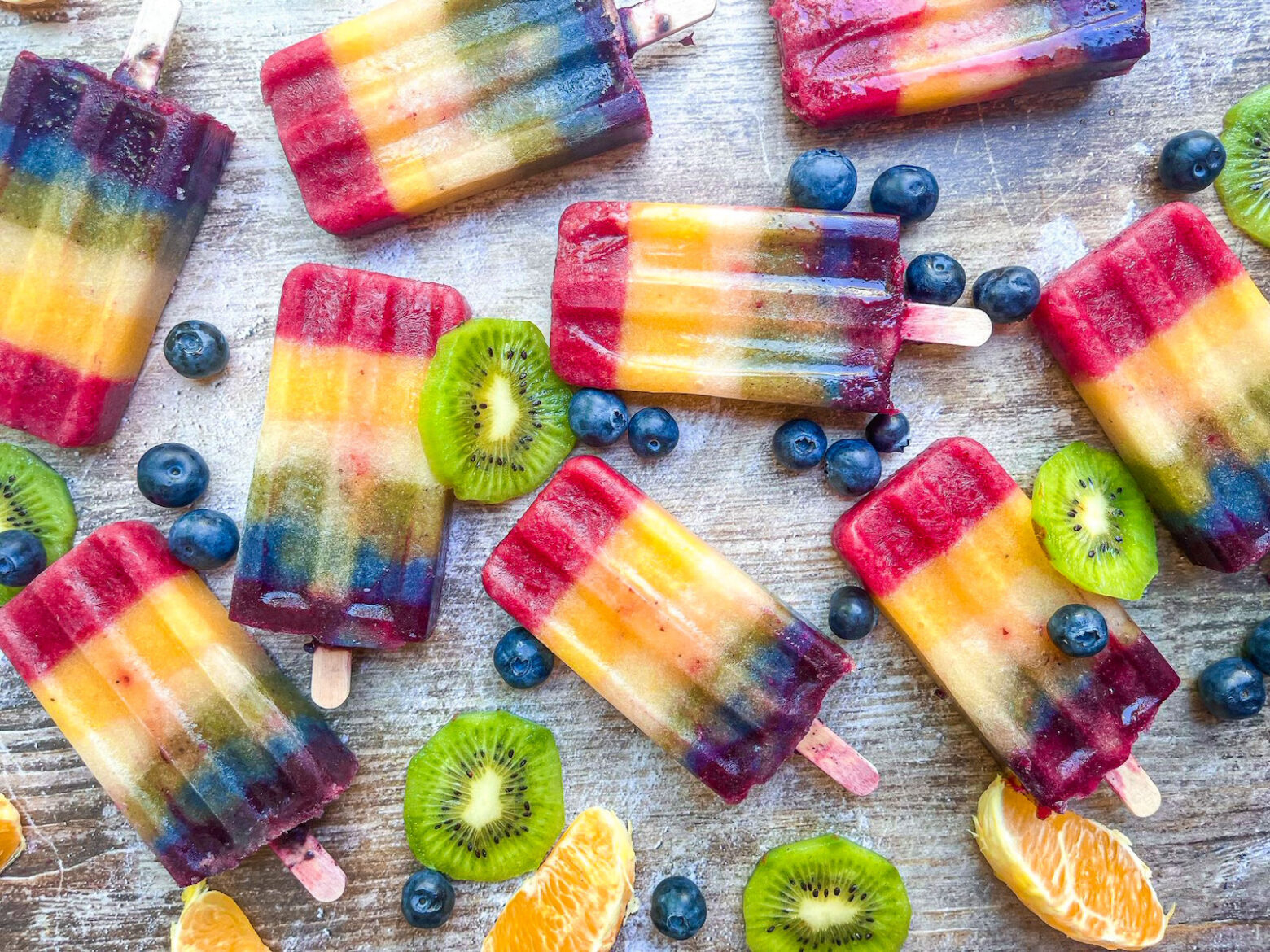 rainbow popsicles on counter with fruits