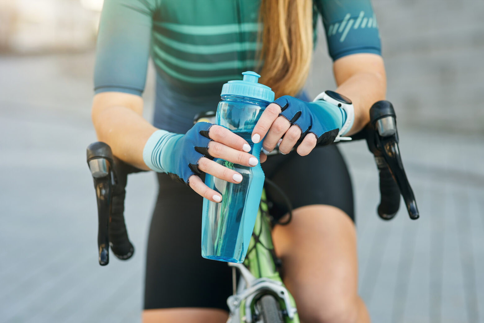 female cyclist holding water bottle on her bike