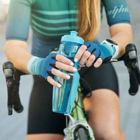 female cyclist holding water bottle on her bike