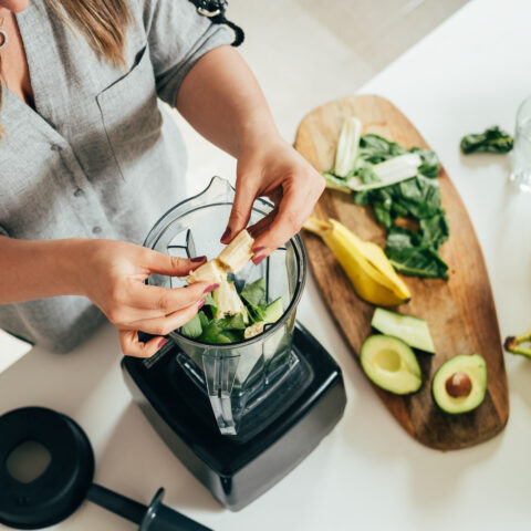 women putting fruit in blender