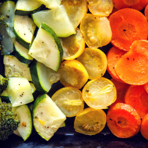 A variety of roasted vegetables arranged by color to make a rainbow