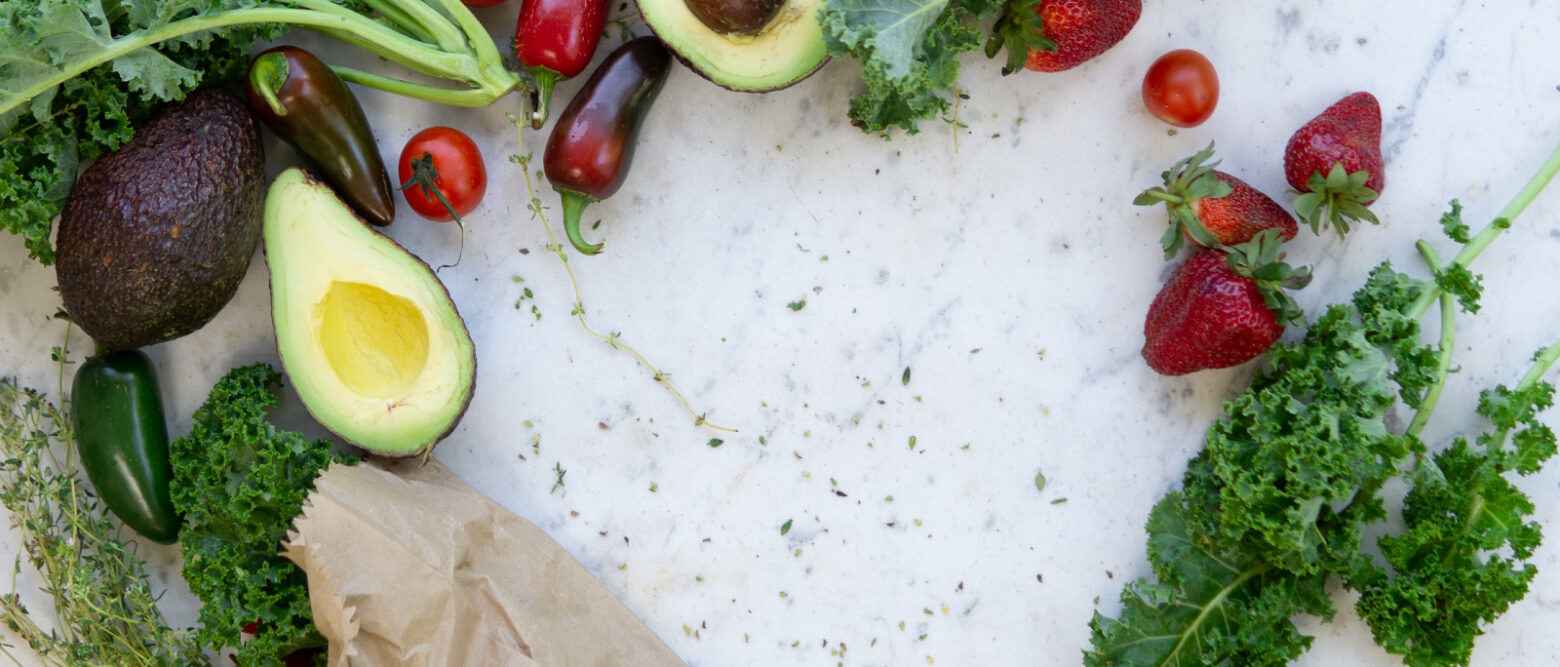 Fresh fruits and vegetables on a white marble countertop